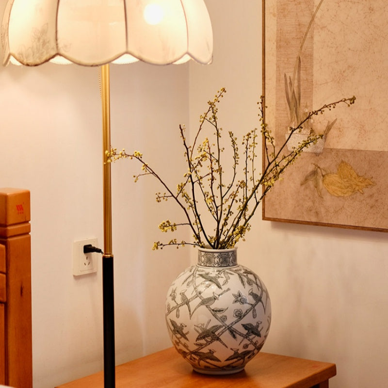 Ceramic bird and branch globular vase on wooden table with lamp