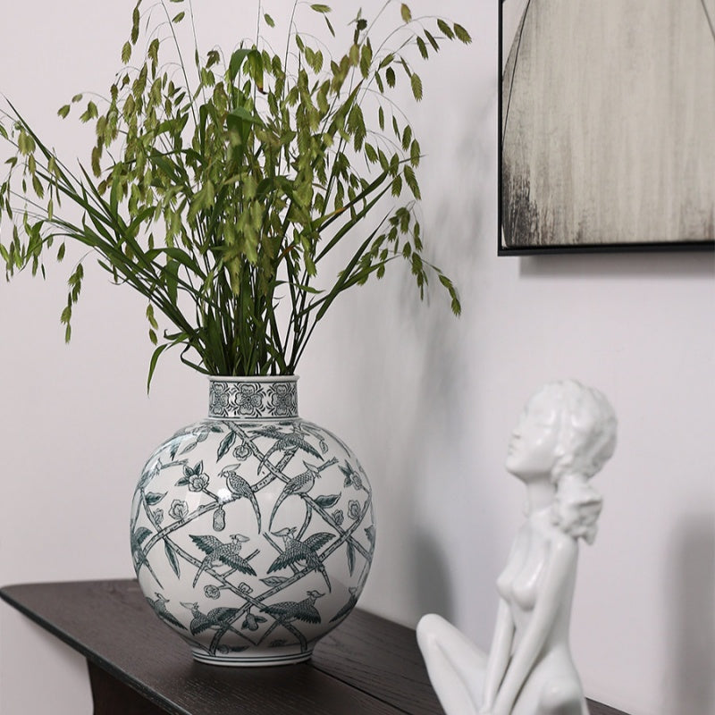 Ceramic vase with green foliage on dark console