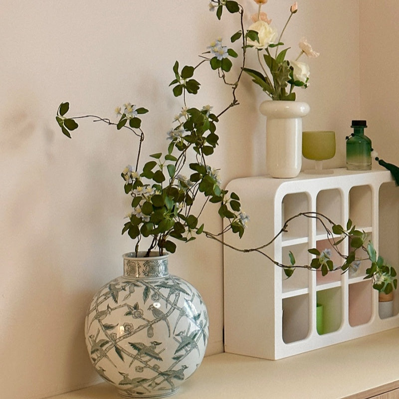 Styled ceramic vase with delicate flowers on white shelf