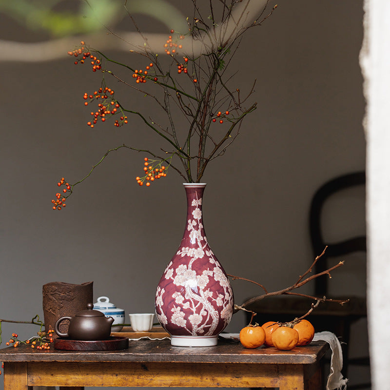 Tall red ceramic vase with white plum blossom design