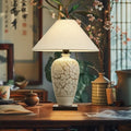 Ceramic floral relief vase table lamp lit in traditional study setting
