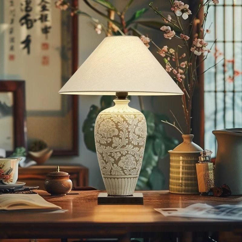 Ceramic floral relief vase table lamp lit in traditional study setting
