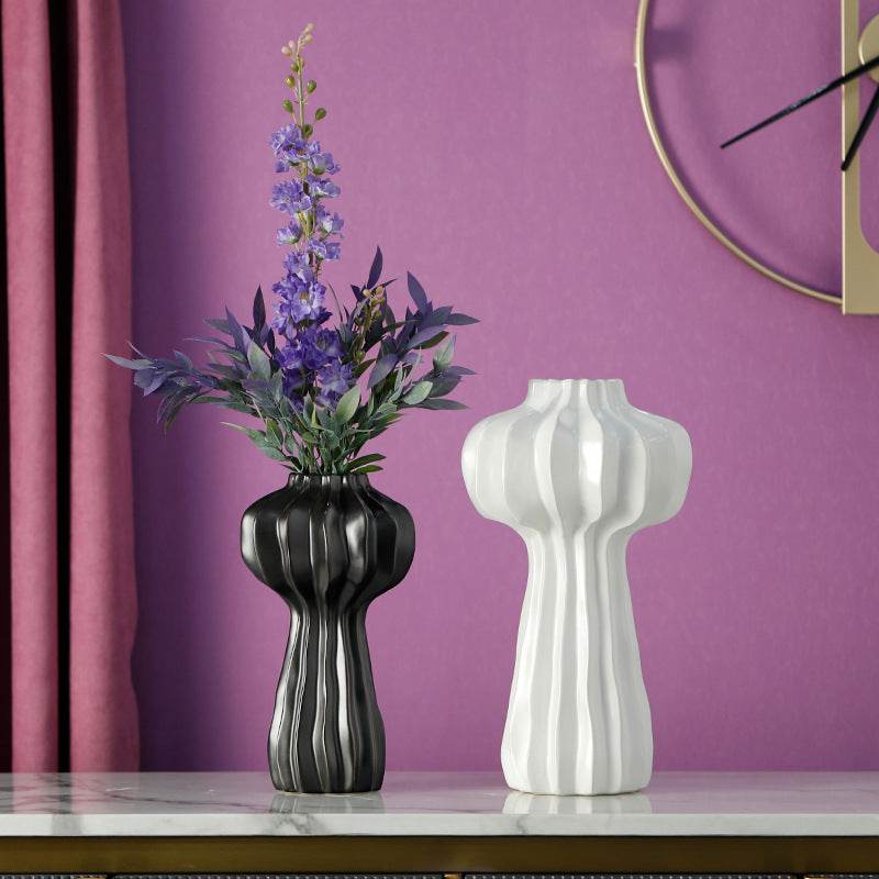 Black and white ceramic fluted vases with floral arrangements on marble table