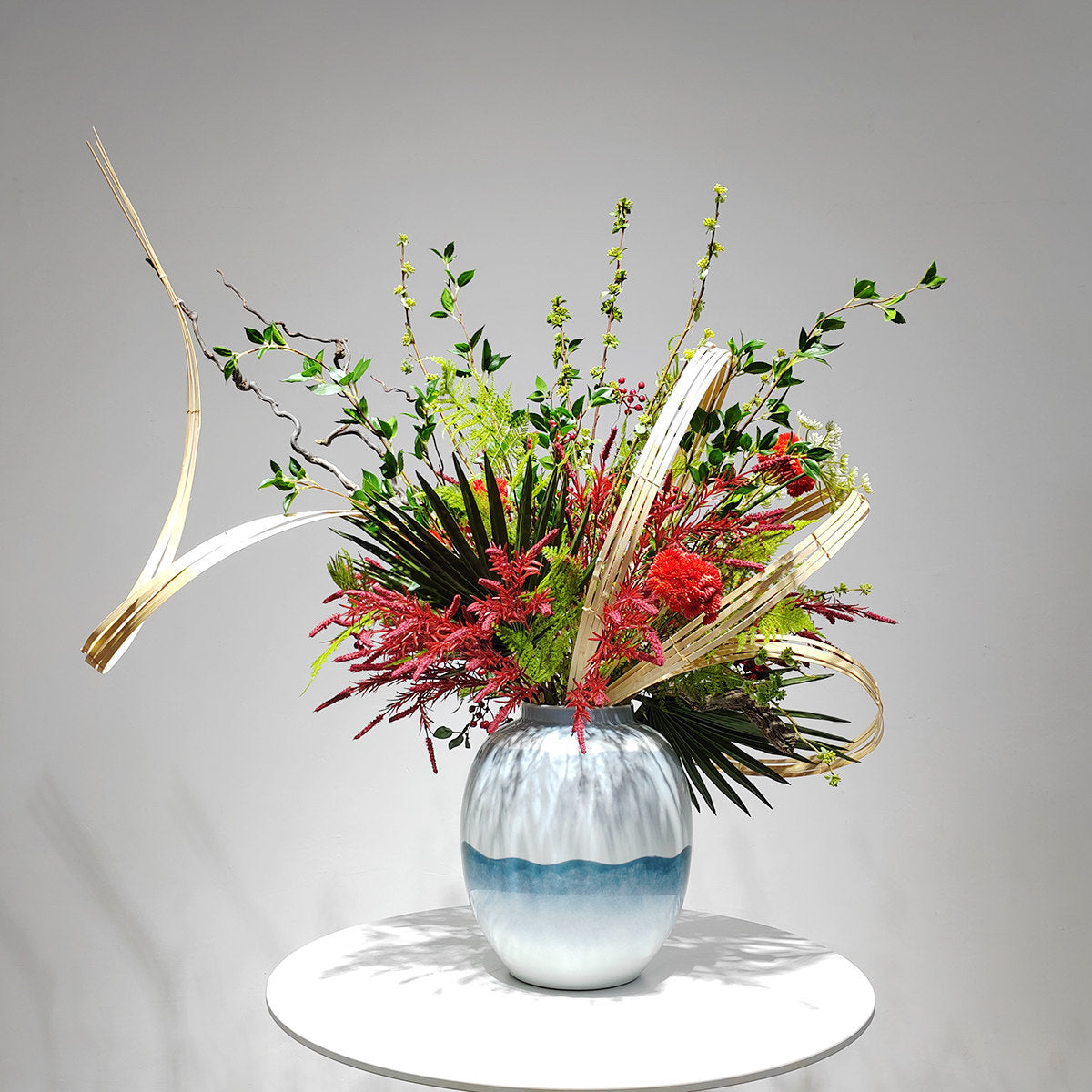 Angled studio view showing bamboo curves and red celosia flowers