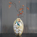 Front view of hand-painted ceramic magnolia and bird vase with floral arrangement