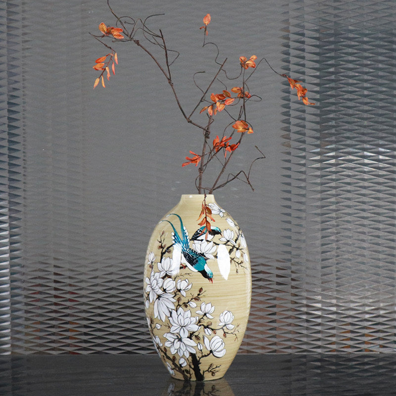 Front view of hand-painted ceramic magnolia and bird vase with floral arrangement