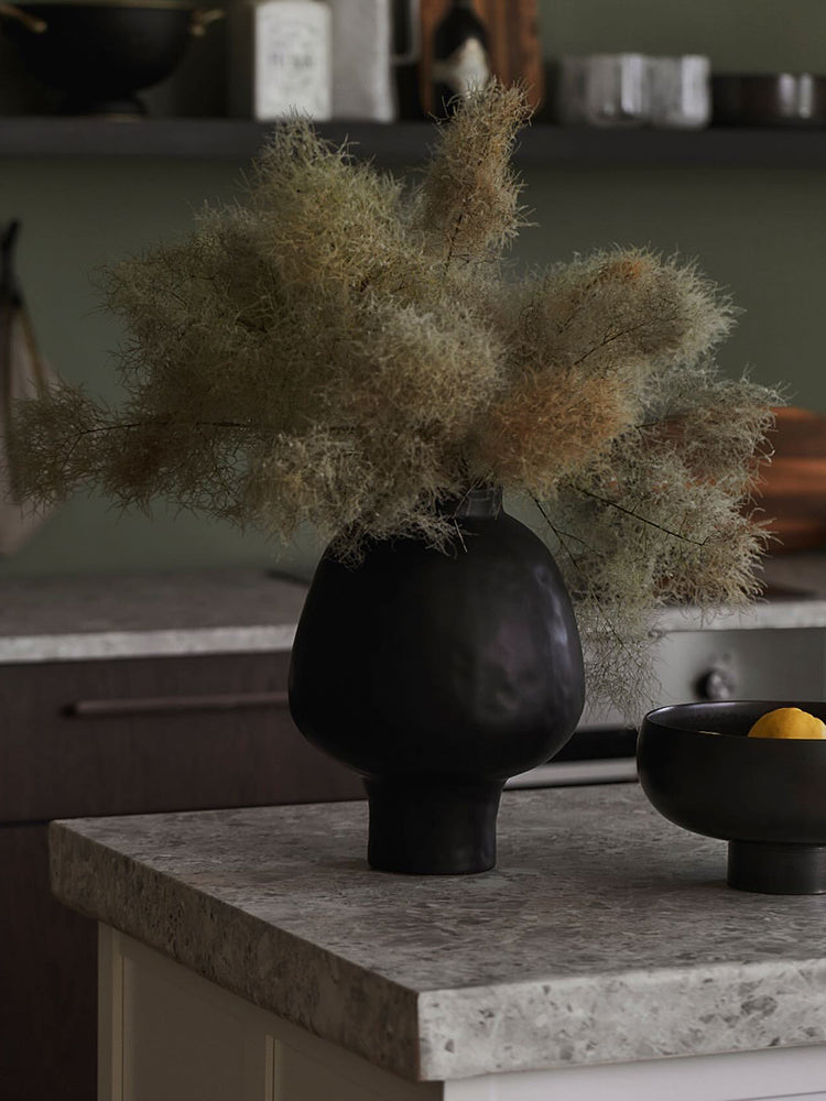 White ceramic vase styled on glass table with blossoming branches
