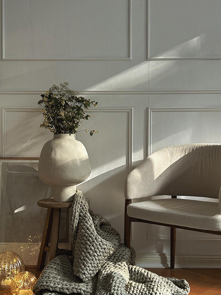 Atmospheric shot of white vase on floor with textured throw
