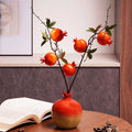 Ceramic pomegranate vase with artificial branches on table