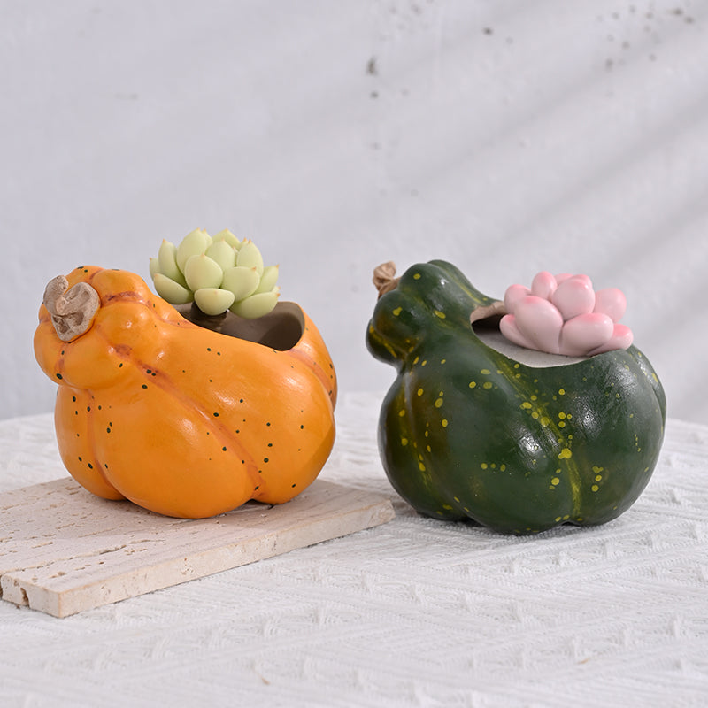 Green and orange ceramic pumpkin planters side by side