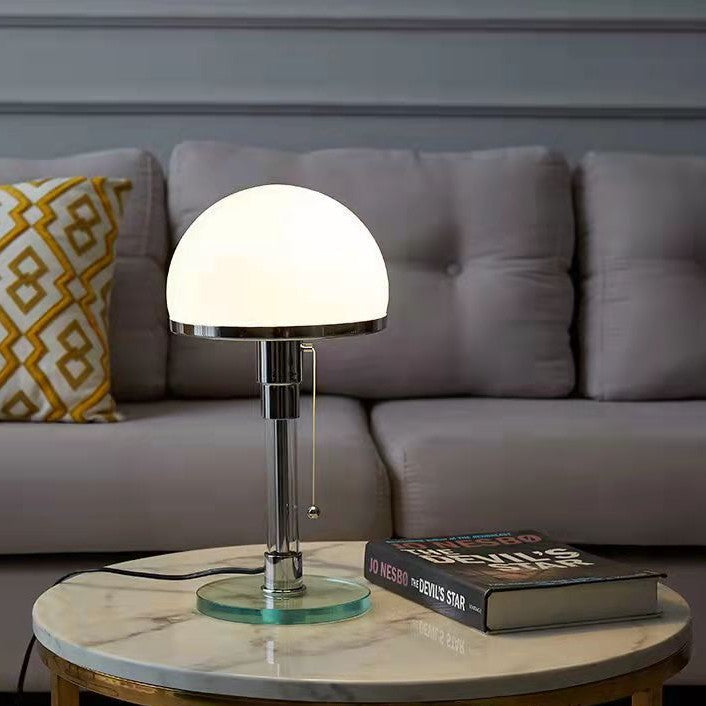 Chrome metal and opal glass table lamp on marble side table