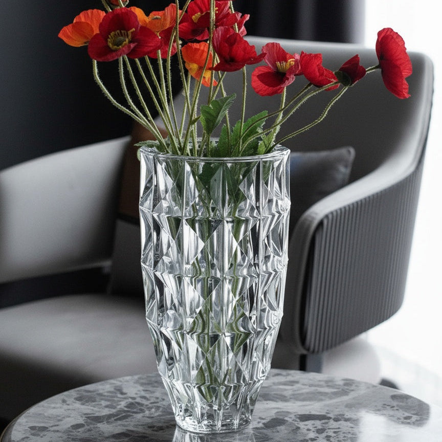Clear crystal geometric vase styled with red flowers on a marble table