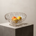 Clear cut glass fruit bowl holding lemons and oranges on marble table