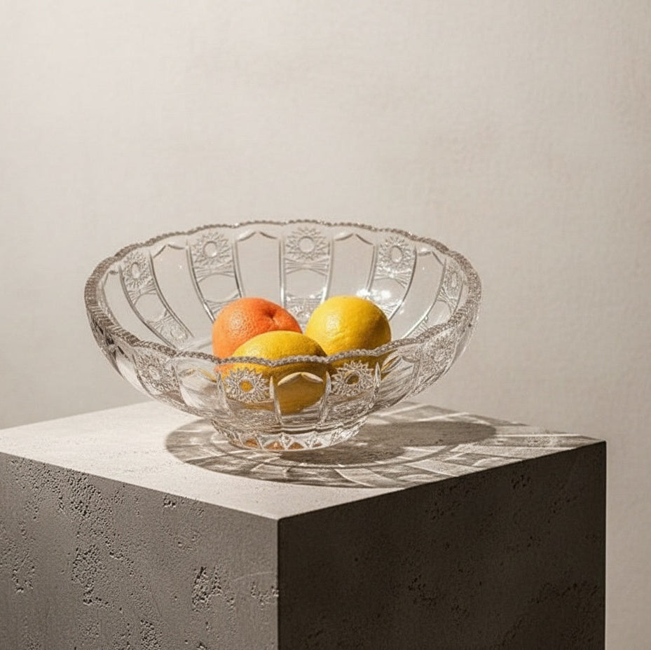Clear cut glass fruit bowl holding lemons and oranges on marble table