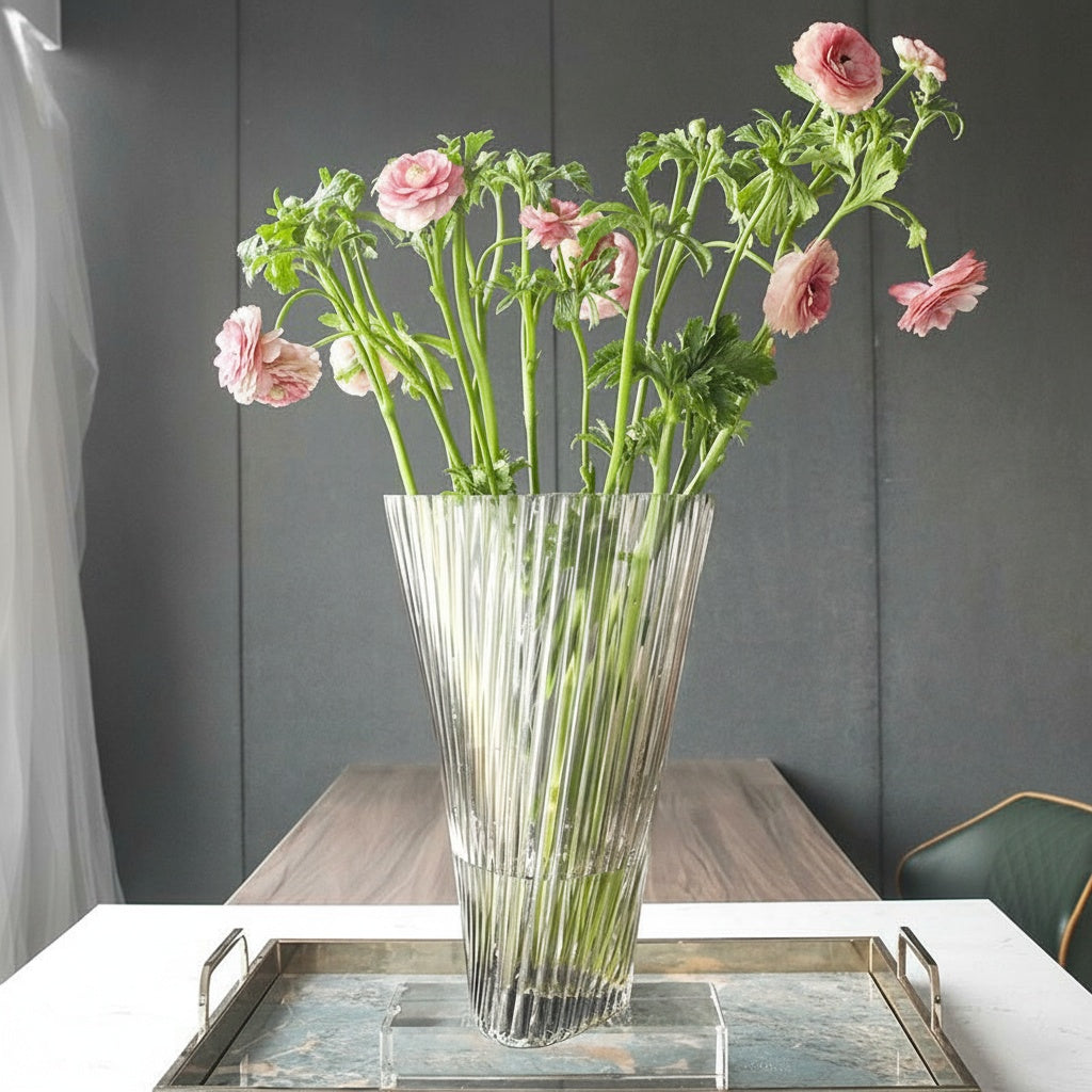 Clear fluted glass flared vase with pink flowers on a tray