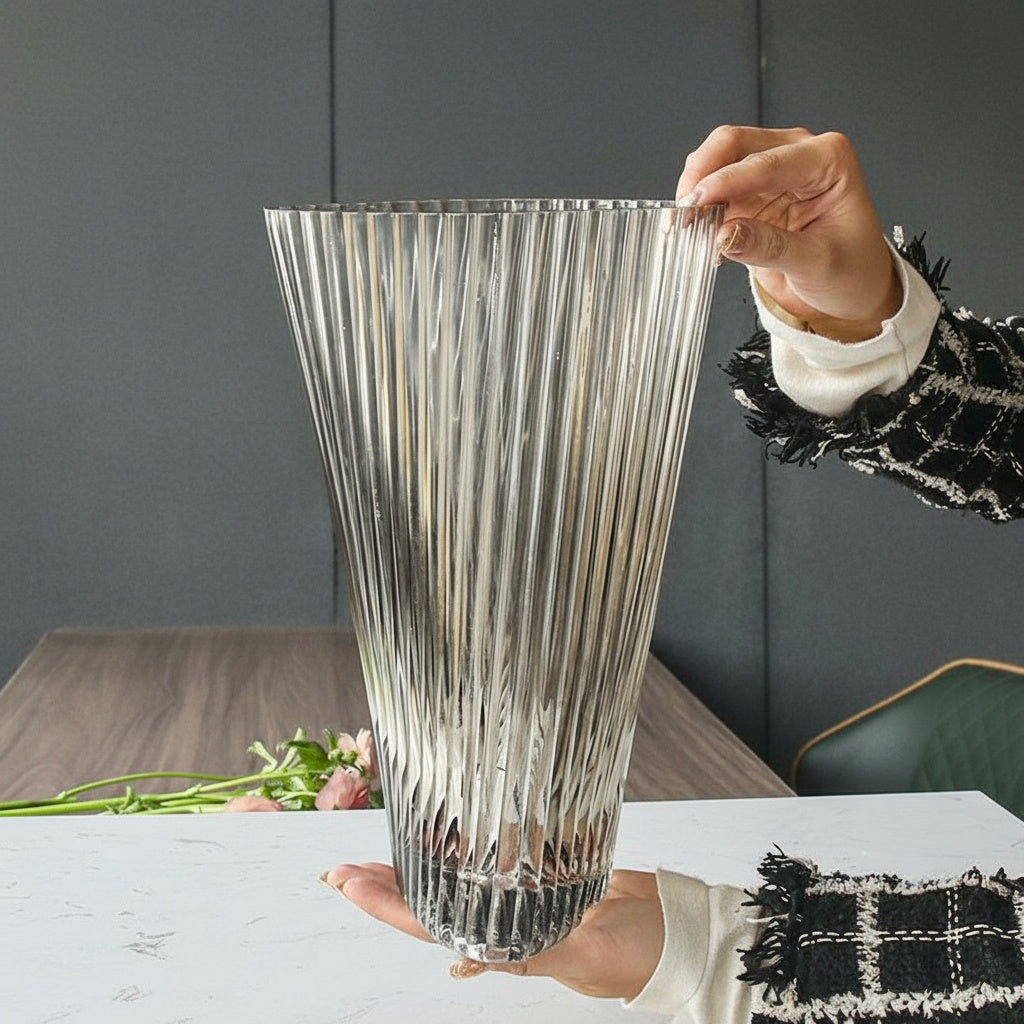 Person holding a large clear ribbed glass vase