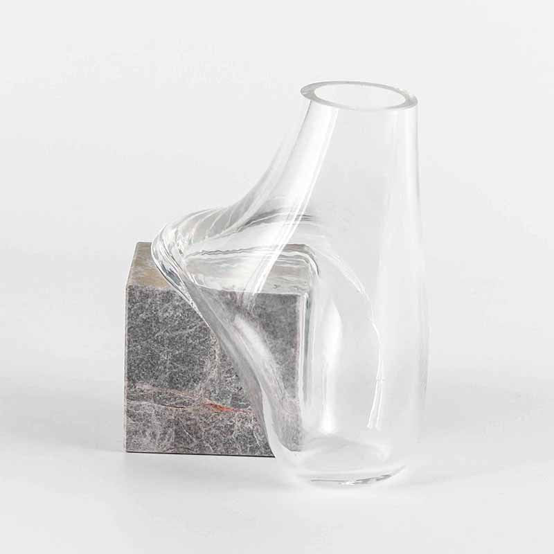 Empty clear glass vase draped over grey stone block
