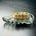 Clear glass sculptural serving dish holding pastries