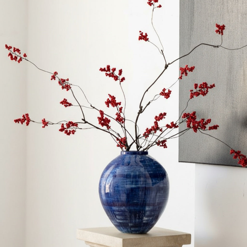 Blue ceramic vase with cross-hatch pattern holding red berries