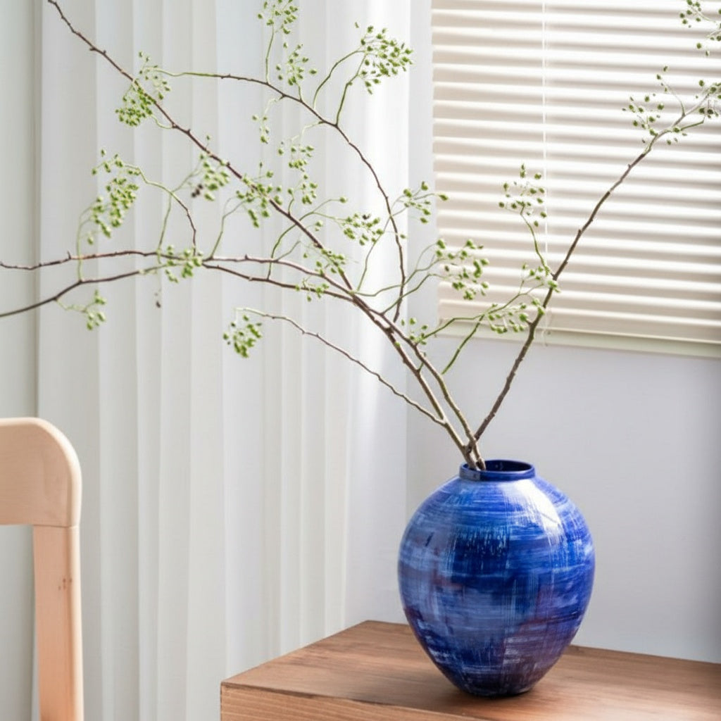 Round cobalt blue vase styled with green branches