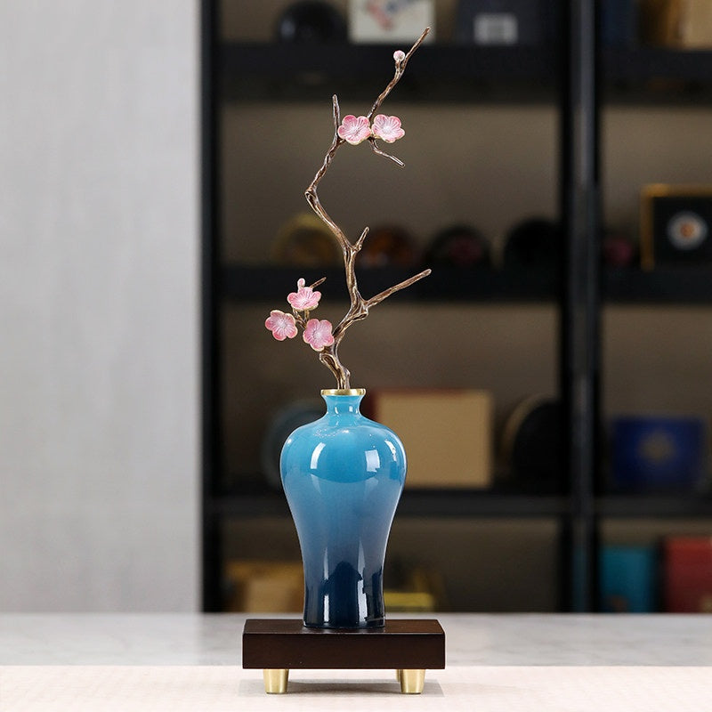 Front view of copper plum blossom branch in blue gradient vase on wooden stand
