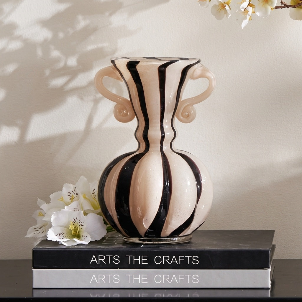 Front view of cream and black striped glass vase on books
