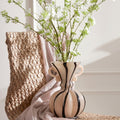 Striped glass vase with scroll handles holding white flowers