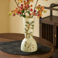 Full view of cream floral hourglass vase on table