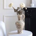 Cream floral ceramic pitcher vase with white flowers on table