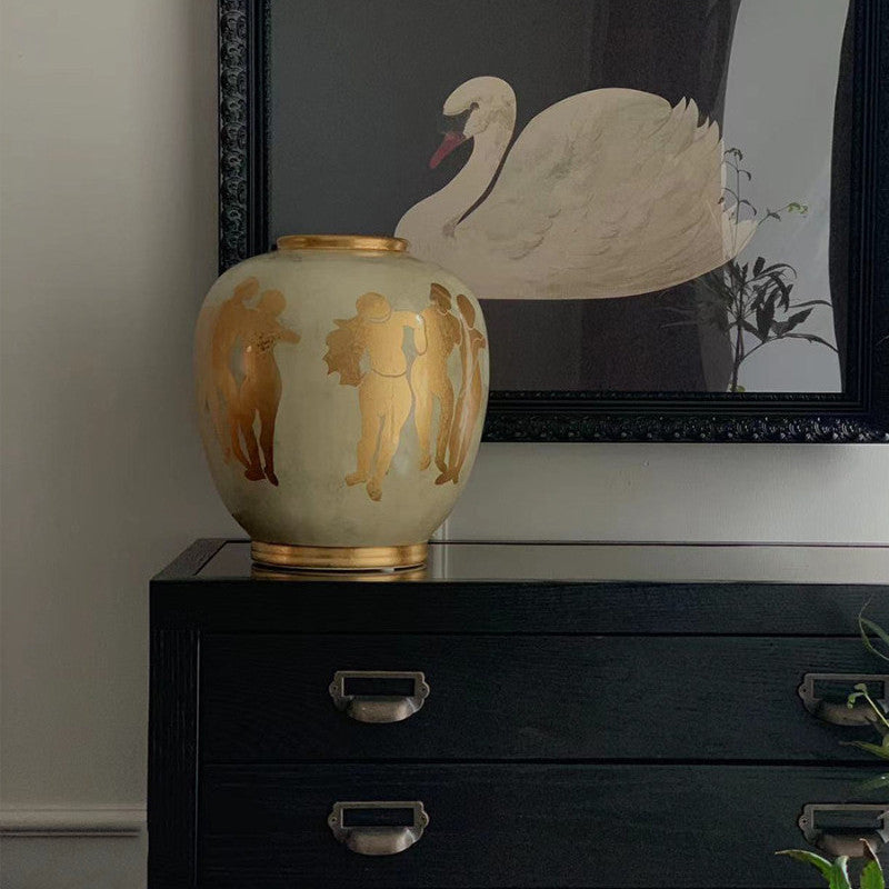 Cream ceramic vase with gold classical figures on black cabinet