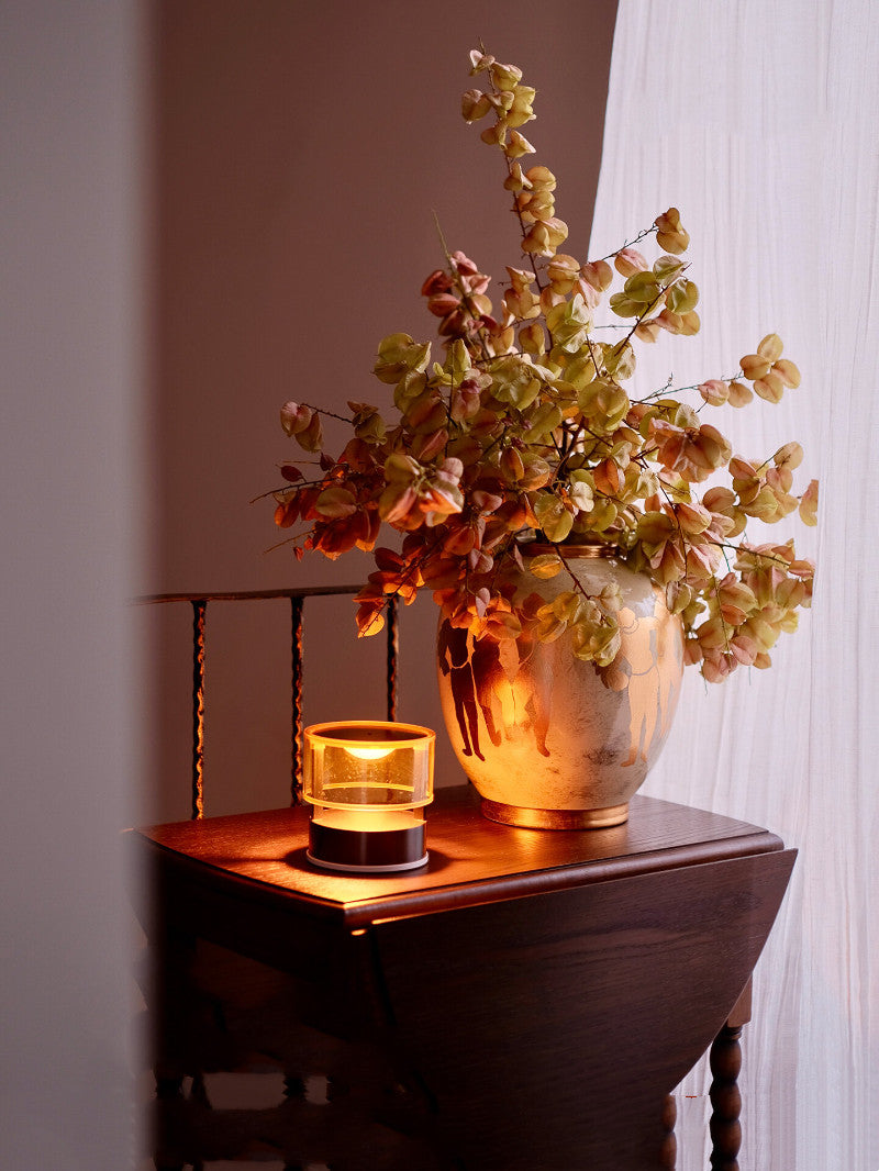 Cream and gold vase with autumn leaves illuminated by warm light