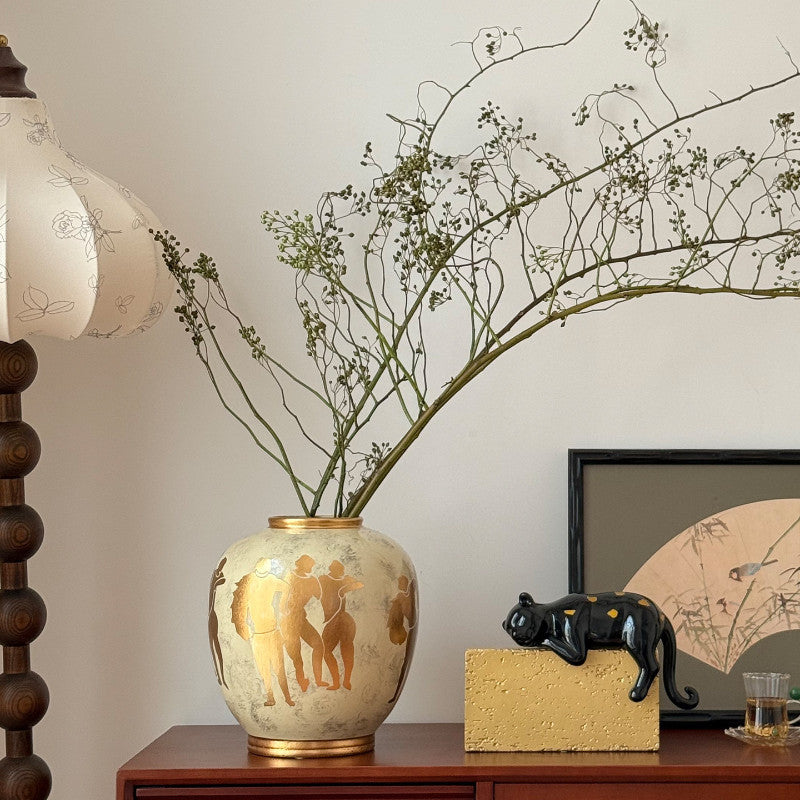 Ceramic vase with gold Grecian motif on wooden sideboard