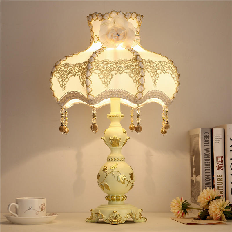 Front view of ornate cream and gold table lamp with lace shade