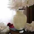 Cream speckled glass vase with black rim holding white peonies