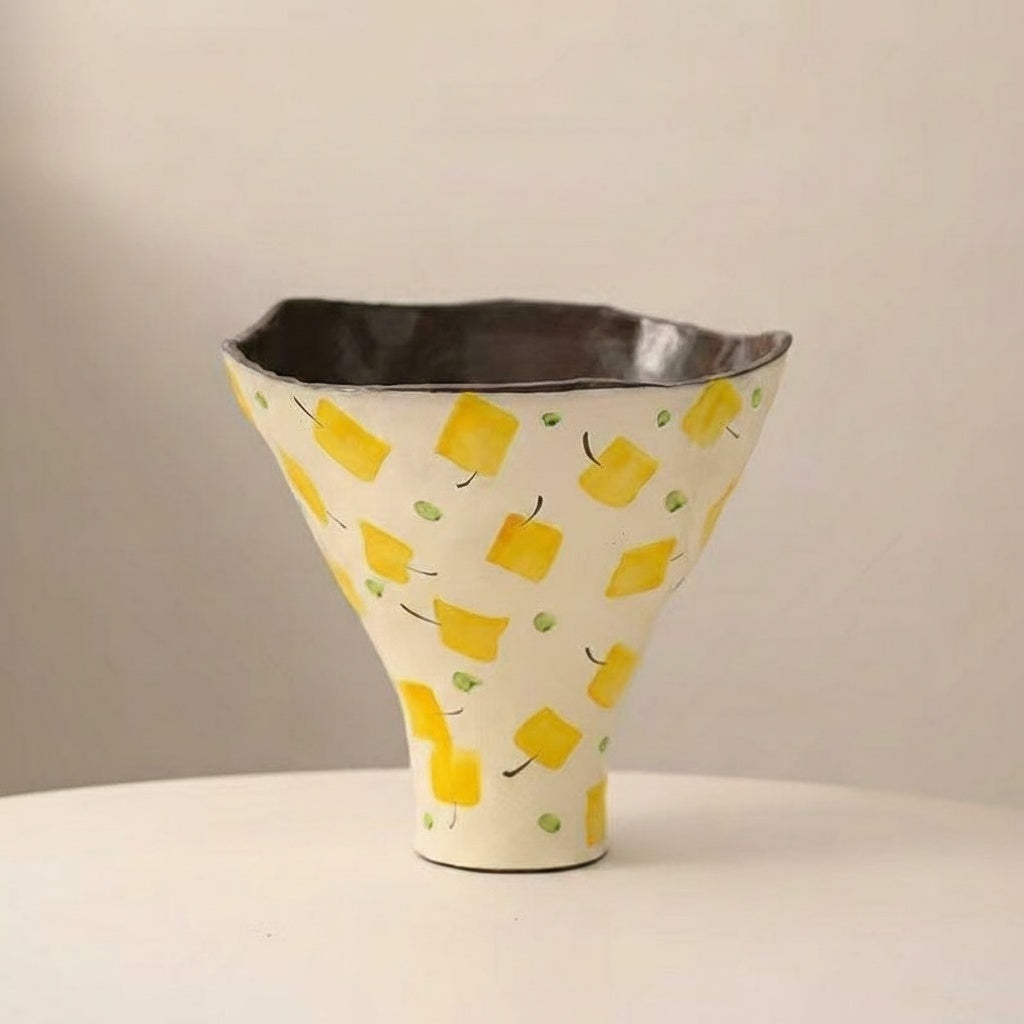Close up of cream ceramic vase with yellow geometric pattern