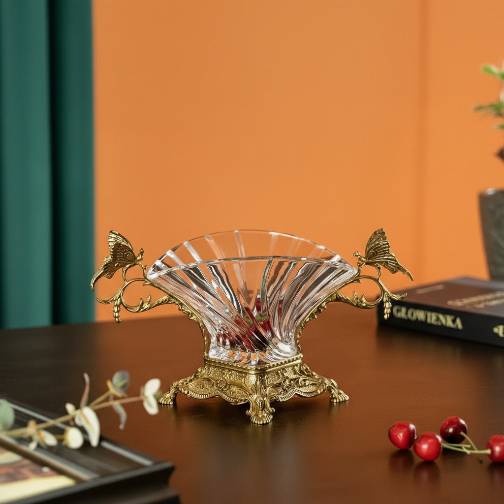 Angled view of crystal fan bowl with brass butterfly handles on table