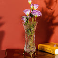 Crystal vase with brass floral vine accents on red background