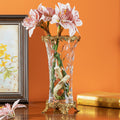 Cut crystal vase with gold brass grapevine rim and base holding pink flowers