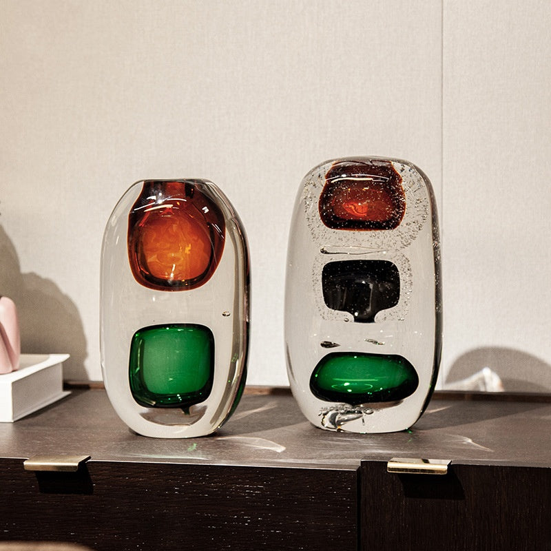 Two crystal glass sculptural vases displayed together on dark wood surface