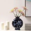 Front view of dark blue ceramic moon flask vase with flowers