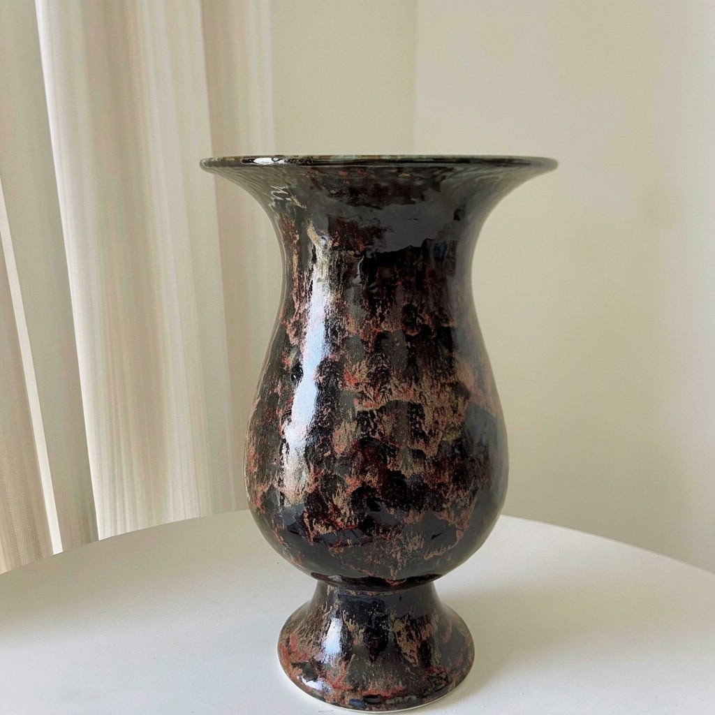 Dark copper glazed ceramic pedestal vase standing empty