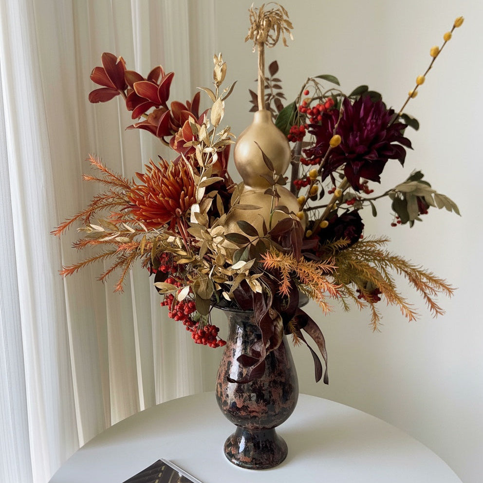 Dark copper glazed ceramic pedestal vase with floral arrangement