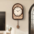 Front view of dark wood arched wall clock with pendulum on wall