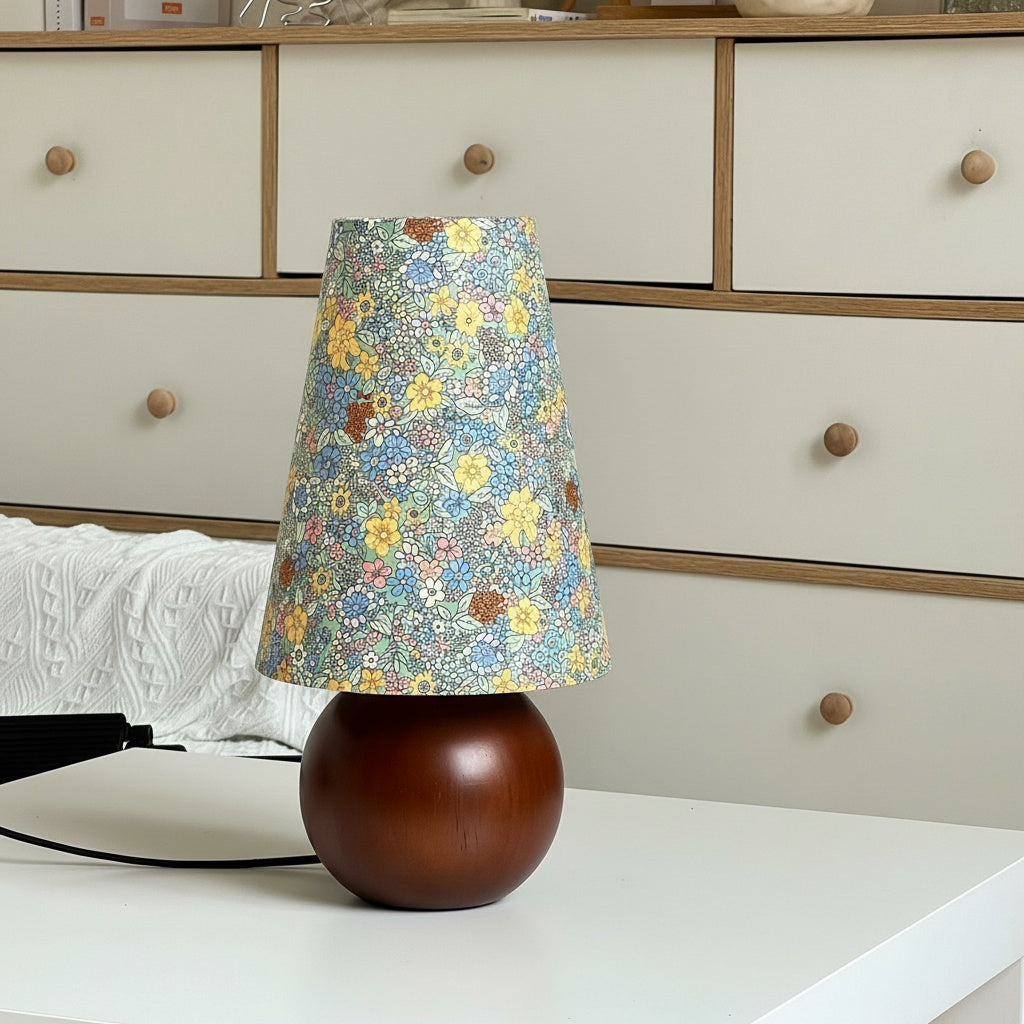 Dark wood spherical table lamp with floral fabric shade on white table