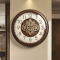 Front view of dark wood wall clock with gear design on wall
