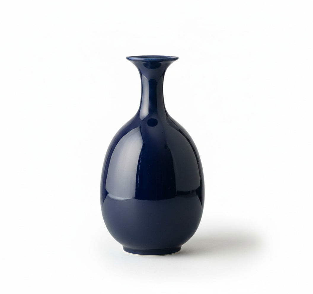 Isolated view of glossy deep blue ceramic bottle vase on white background