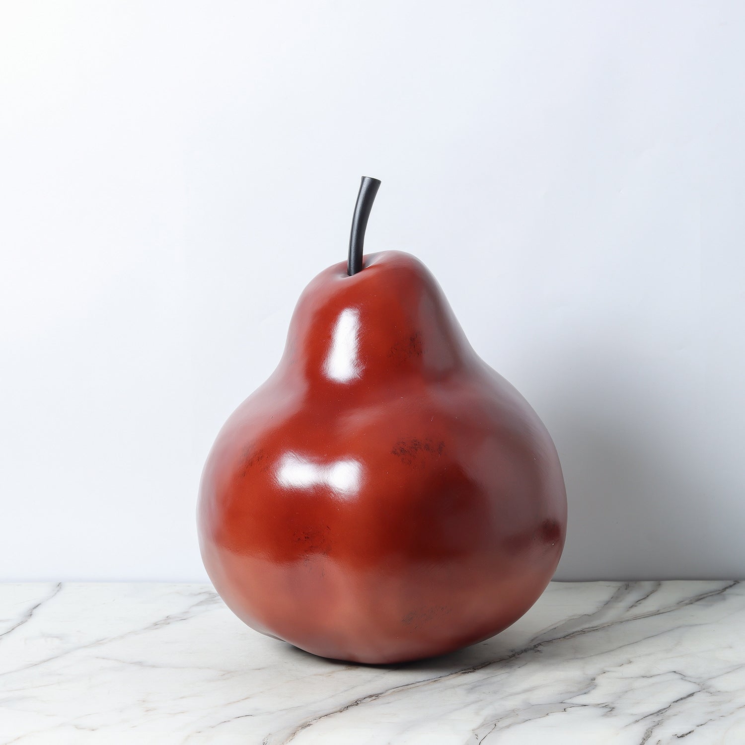 Front view of deep red resin pear sculpture against white background
