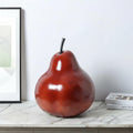 Deep red resin pear sculpture displayed on marble surface in modern interior