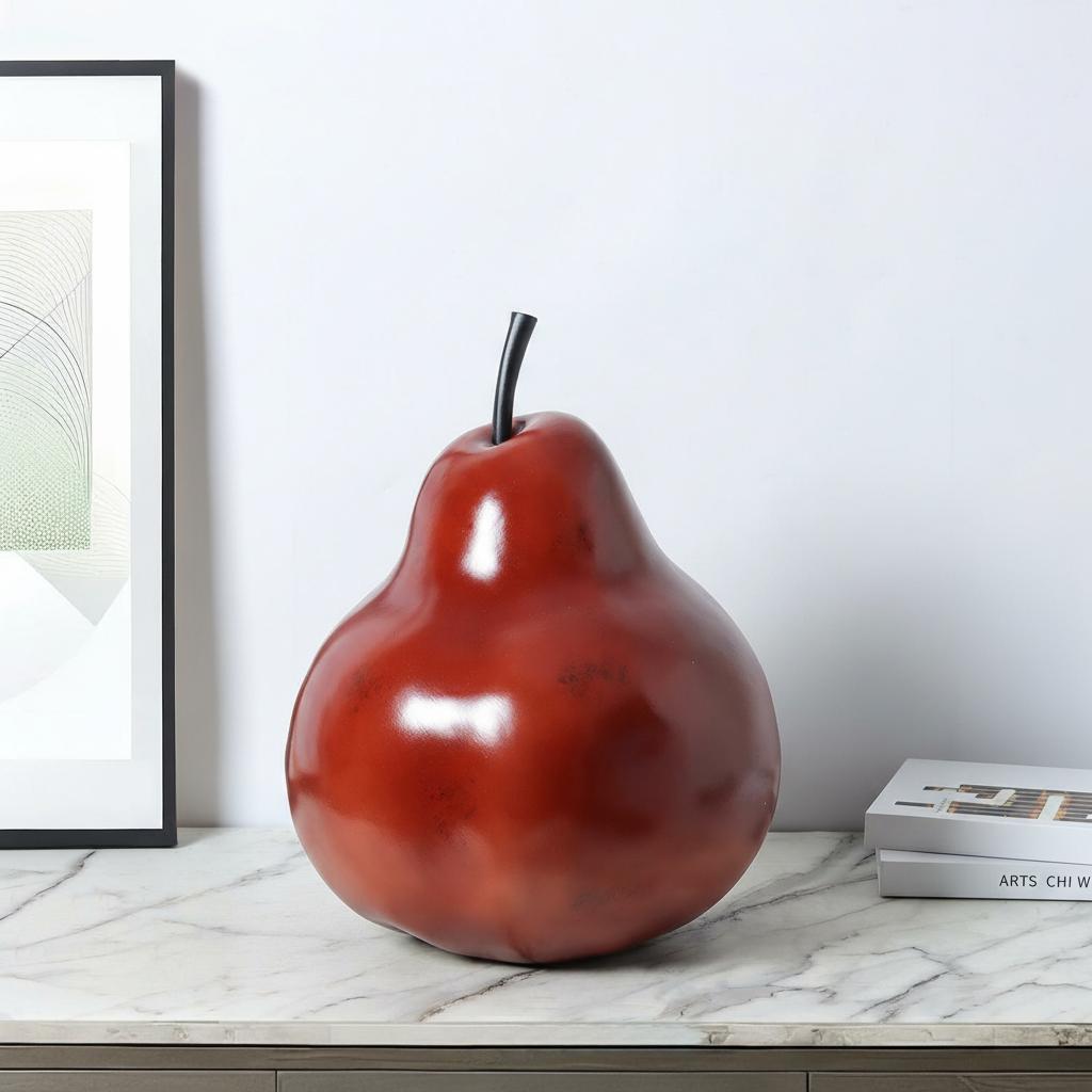 Deep red resin pear sculpture displayed on marble surface in modern interior