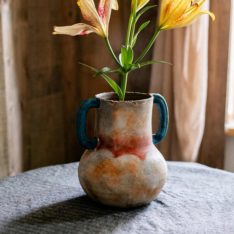 Distressed ceramic amphora vase with blue handles and lilies